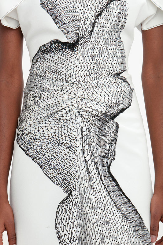Close-up of a Victoria Beckham white fit-and-flare dress with a black abstract fishnet design, focusing on a detailed bow at the waist.