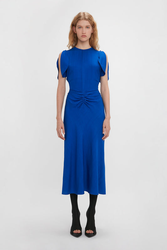 A woman in a Victoria Beckham Palace Blue Gathered Waist Midi Dress.