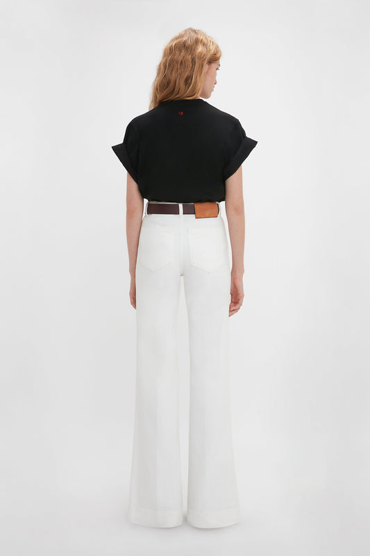 Woman seen from behind wearing a Victoria Beckham 'Do As I Say, Not As I Do' Slogan T-Shirt In Black and white wide-leg trousers with a brown belt against a plain background.