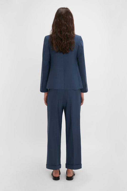 A woman in a Victoria Beckham Shrunken Double Breasted Jacket In Heritage Blue stands with her back to the camera on a white background.