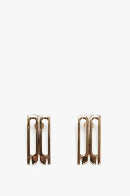 Two Victoria Beckham gold-plated brass Exclusive Frame Stud Earrings In Gold with rectangular outlines and internal comb structures, positioned vertically on a white background.