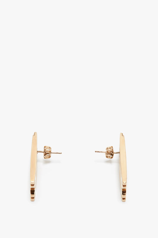 A pair of Victoria Beckham Exclusive Frame Stud Earrings In Gold on a white background, positioned vertically with earring backs visible.