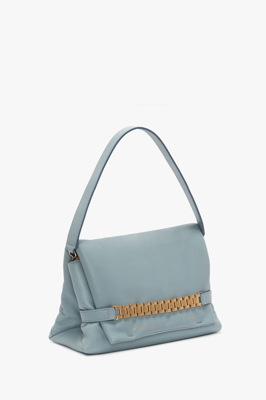 Pale blue Nappa leather Puffy Chain Pouch with strap in ice leather by Victoria Beckham, featuring a structured design, a golden metallic clasp on the front, and a single shoulder strap, isolated on a white background.