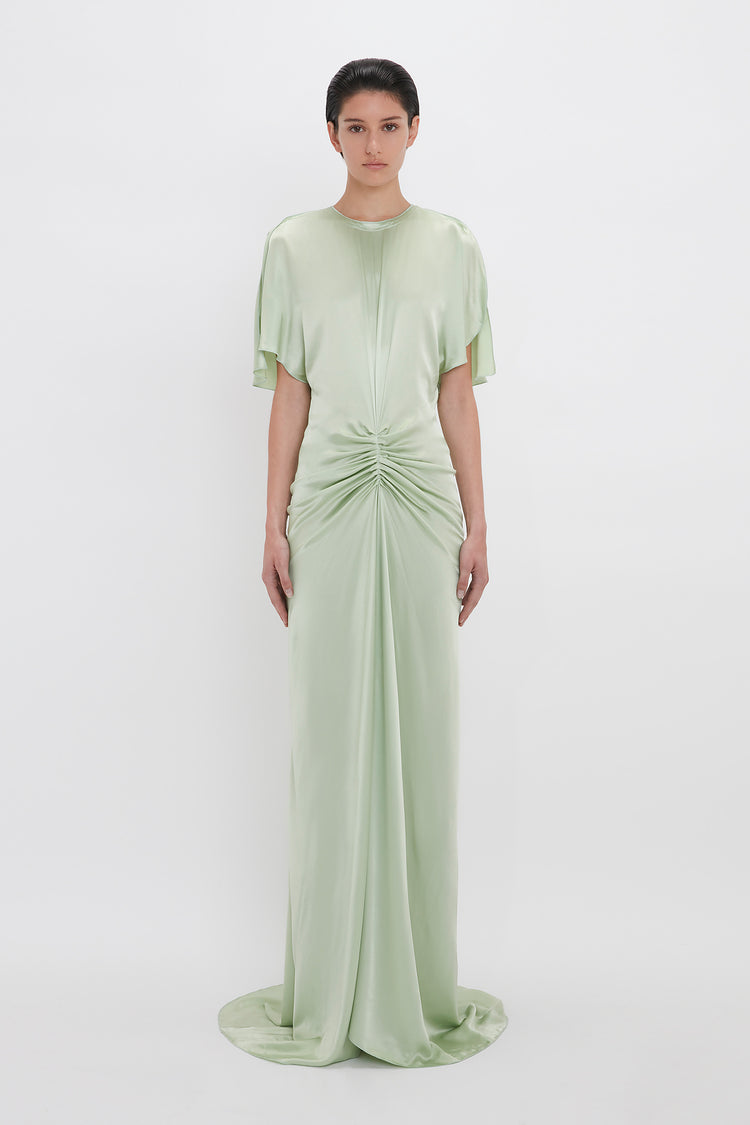 Woman in a Victoria Beckham Exclusive Floor-Length Gathered Dress In Jade with short sleeves and a ruched waist, standing against a plain white background.