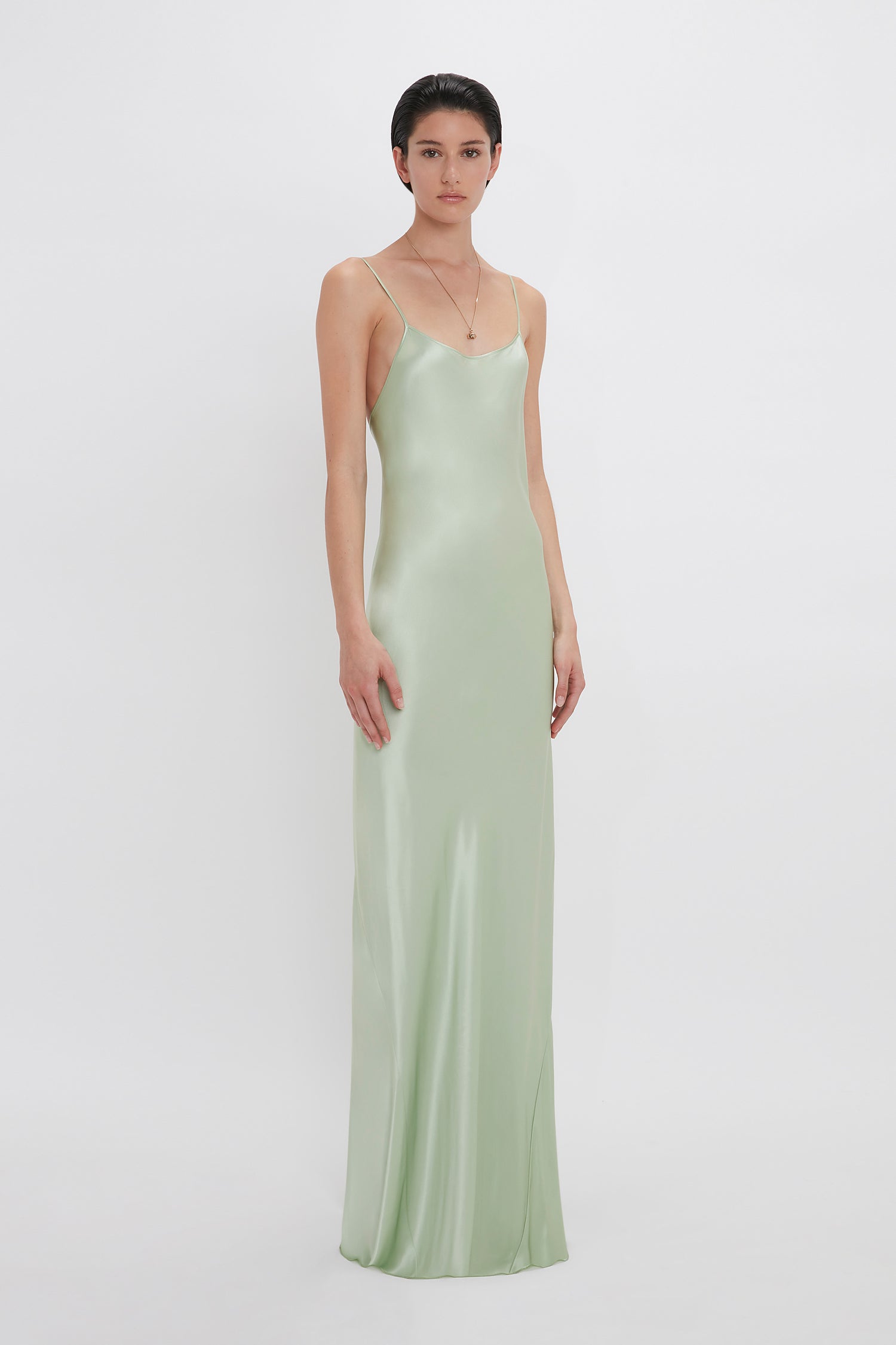 Woman in an Exclusive Low Back Cami Floor-Length Dress In Jade by Victoria Beckham standing against a plain white background.