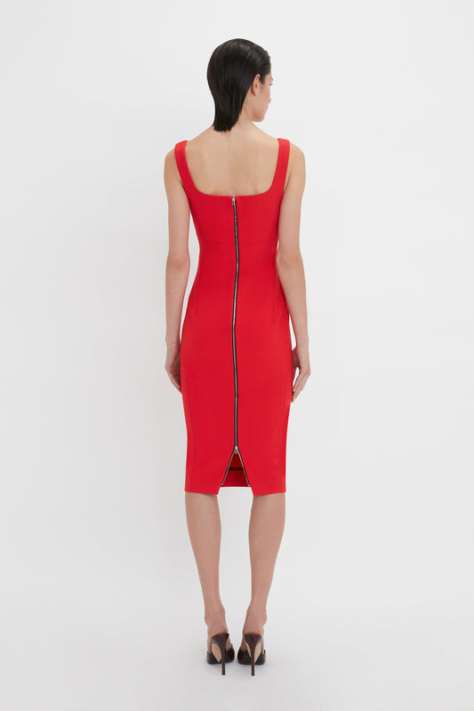 A woman viewed from behind, wearing a Victoria Beckham Sleeveless Fitted T-Shirt Dress In Bright Red with a sweetheart neckline and black heels, standing against a white background.