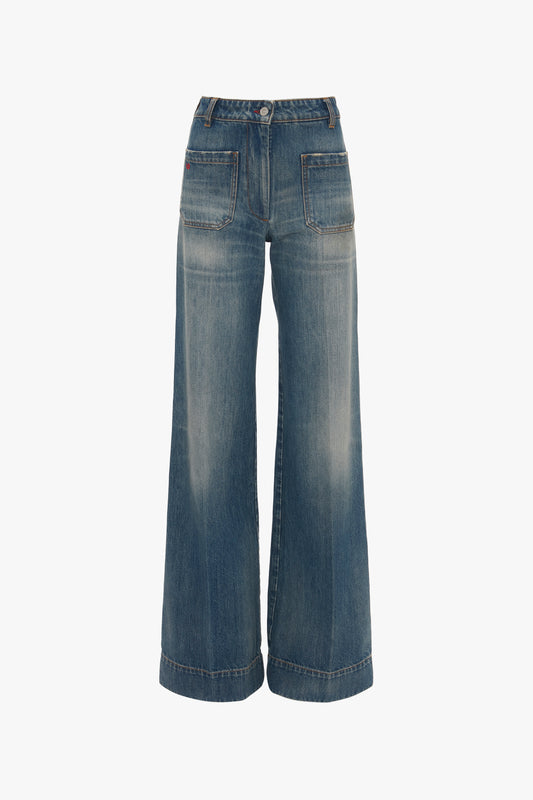 A pair of blue wide-leg vintage denim jeans with visible stitching and a button fastener, isolated on a white background, Victoria Beckham's Alina Jean In Indigrey Wash.