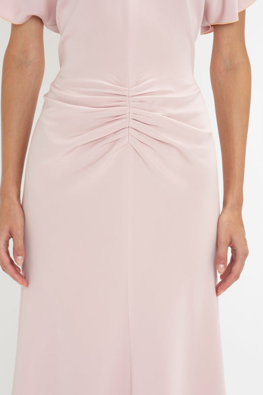 Close-up of a woman in an elegant Victoria Beckham midi dress with a focus on the ruched detail at the lower back.