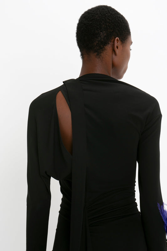 Rear view of a person in a Victoria Beckham Slash-Neck Ruched Midi Dress In Black, photographed against a white background.