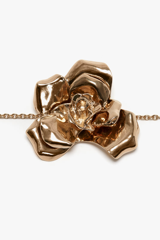A glossy, rose-shaped, gold pendant on an adjustable chain against a white background. 

can be replaced with:

The Exclusive Flower Bracelet In Gold by Victoria Beckham, a rose-shaped gold pendant on an adjustable chain against a white background.