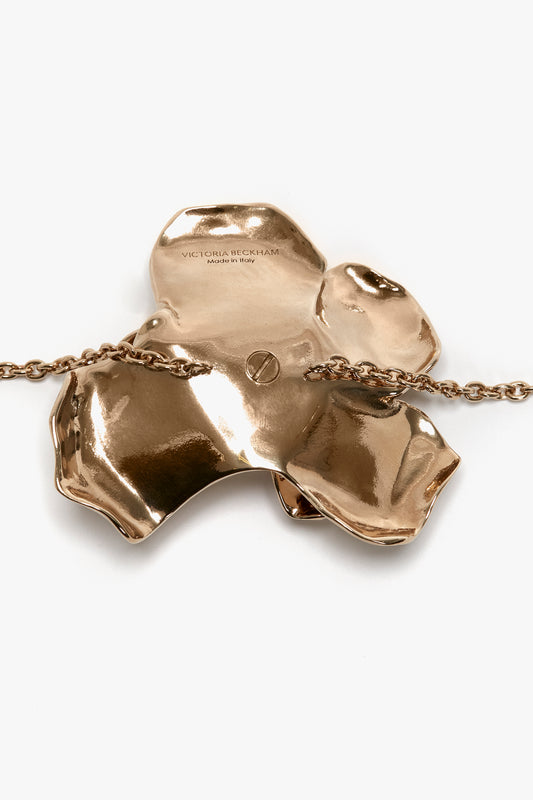 Exclusive Flower Bracelet In Gold, a Victoria Beckham product, with a glossy finish and an inscribed brand name, attached to an adjustable chain, against a white background.