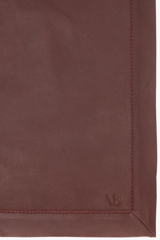 Close-up of a supple brown Victoria Beckham leather bag showing detailed stitching and an embossed letter 'b' logo.