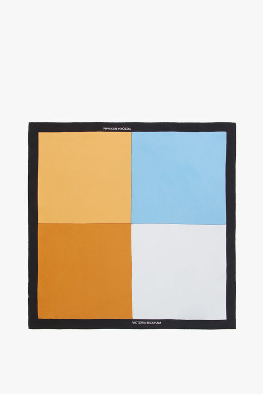 A square scarf featuring a geometric design with large blocks of orange, gold, blue, and white, bordered by black with a small *Victoria Beckham Foulard* logo in the corner.