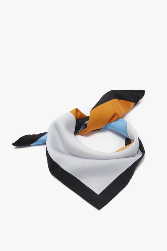 A printed silk twill scarf with diagonal stripes in black, white, blue, and mustard yellow colors, elegantly draped, isolated on a white background by Victoria Beckham.