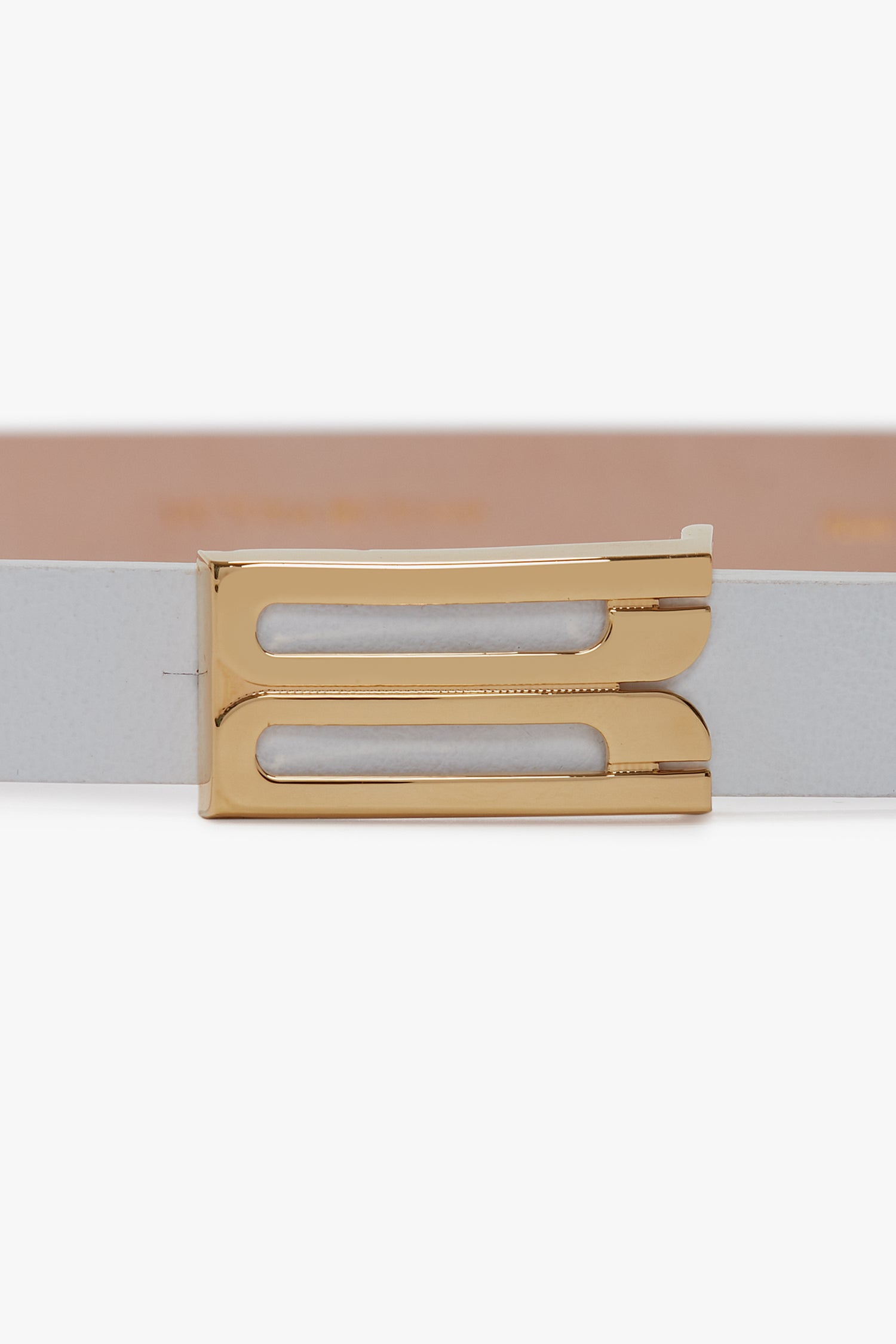 A close-up of a beige Victoria Beckham Exclusive Micro Frame Belt In White Leather with a gold rectangular buckle.