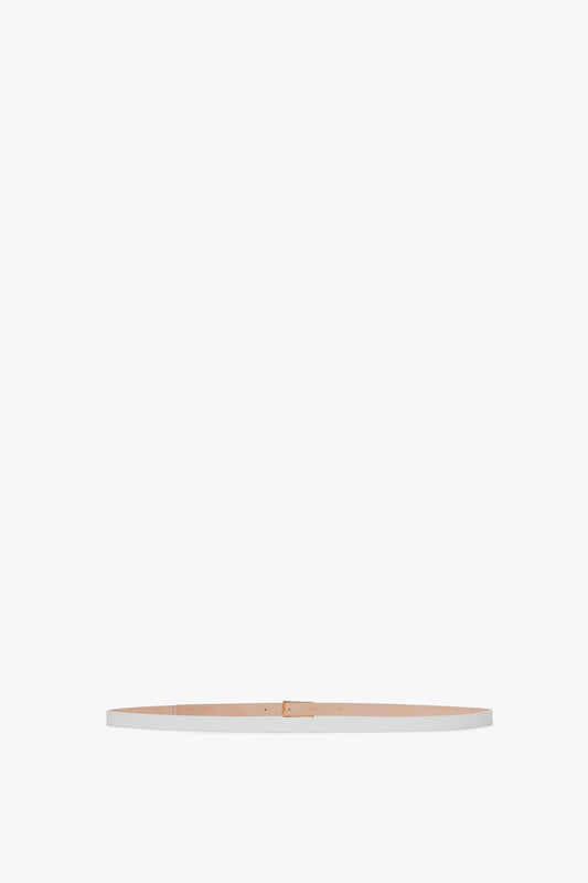 A slim, beige calf leather Exclusive Micro Frame Belt in White Leather with a small gold buckle, displayed against a plain white background by Victoria Beckham.
