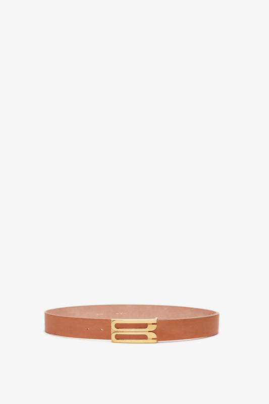 A slim, tan calf leather belt with a gold rectangular buckle, displayed against a white background, like the Exclusive Jumbo Frame Belt In Nude Leather by Victoria Beckham.