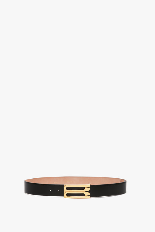 A slim black Exclusive Jumbo Frame belt in calf leather with a gold buckle, isolated on a white background by Victoria Beckham.
