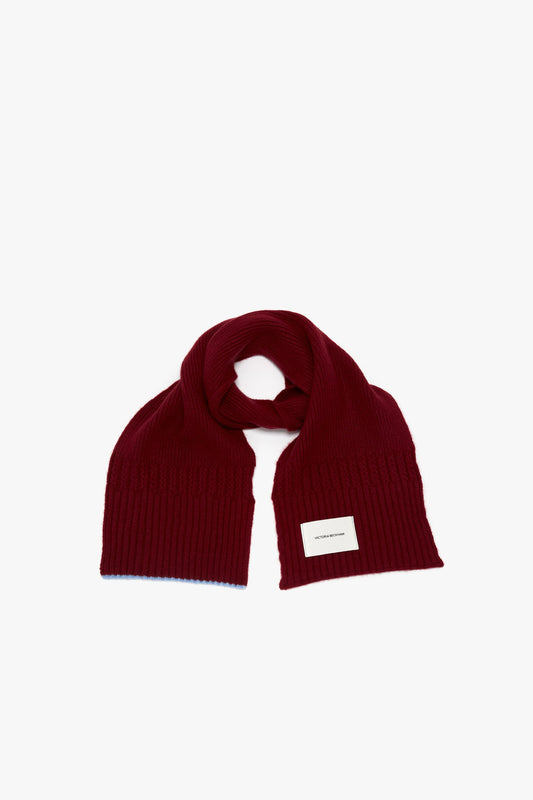 A red knitted luxury scarf with a small Victoria Beckham logo label, displayed flat on a white background.