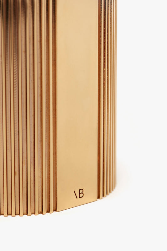 Close-up image of a standing book with focus on its pages and spine, showing texture and the initials "nb" at the bottom right corner of the Victoria Beckham Exclusive Perfume Cuff In Gold.