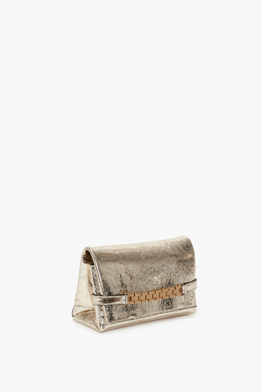 A Victoria Beckham Mini Chain Pouch With Long Strap In Gold Leather with a textured finish and a horizontal strap closure, displayed against a white background.