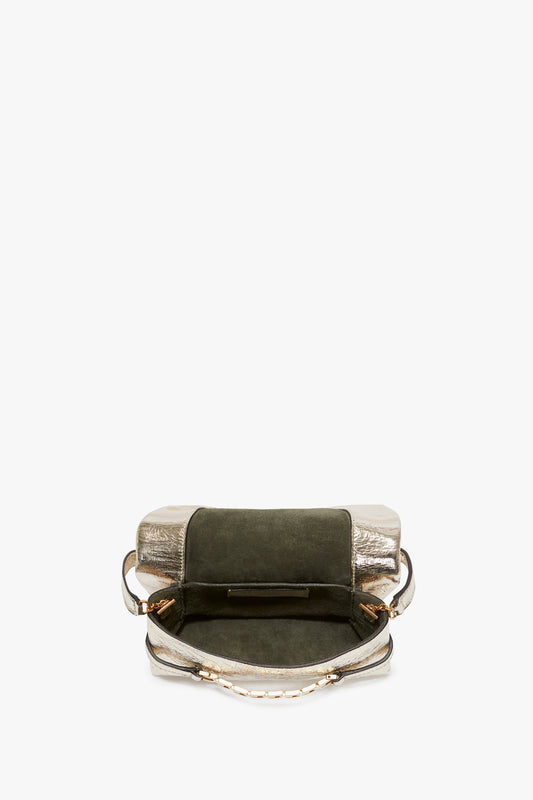 An open, stylish Victoria Beckham Mini Chain Pouch With Long Strap In Gold Leather with a metallic silver bottom and a dark green flap, displayed against a white background.