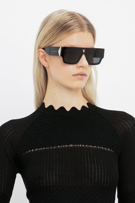 A woman wearing Victoria Beckham's V Plaque Frame Sunglasses In Black.