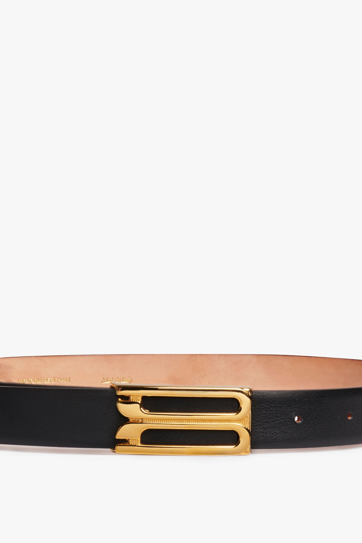 A Victoria Beckham black leather Frame Buckle Belt featuring a polished gold frame buckle, detailed with engraving, set against a white background.