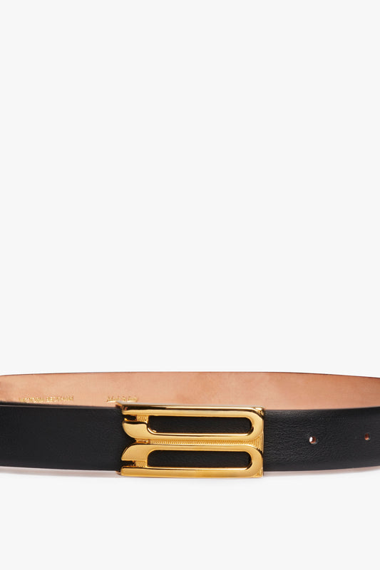 A Victoria Beckham black leather Frame Buckle Belt featuring a polished gold frame buckle, detailed with engraving, set against a white background.
