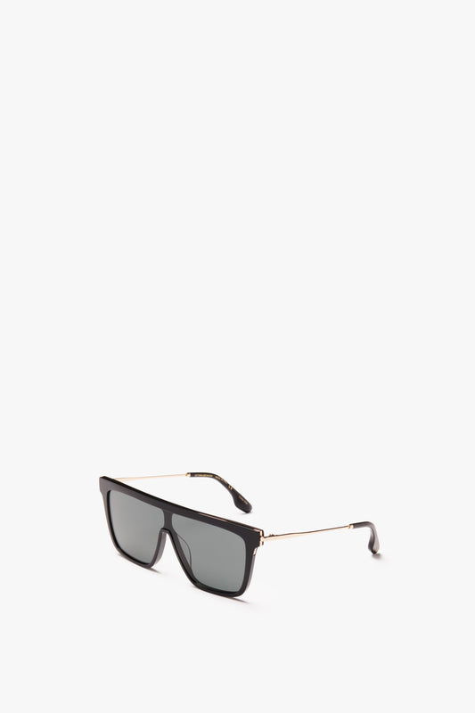 A pair of all-black Victoria Beckham Rectangular Shield Sunglasses with gold detailing on the arms, isolated on a white background.