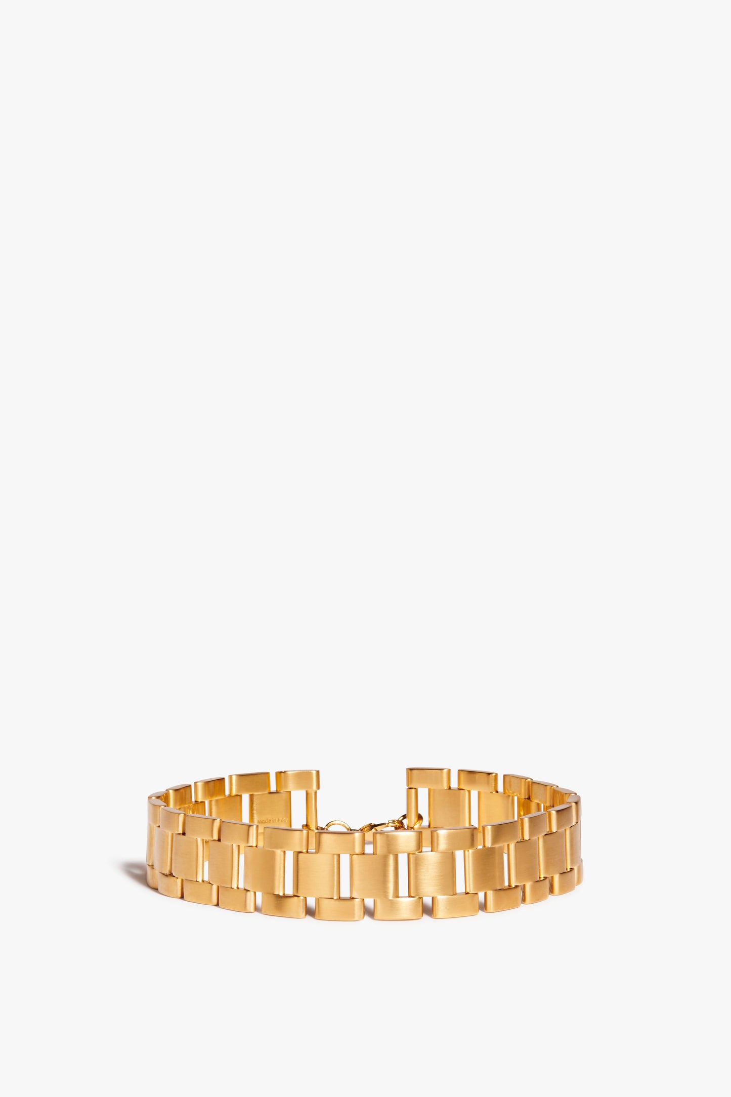 A wide gold bracelet with a linked design, reminiscent of a Watch Chain Choker In Gold by Victoria Beckham, displayed against a plain white background.