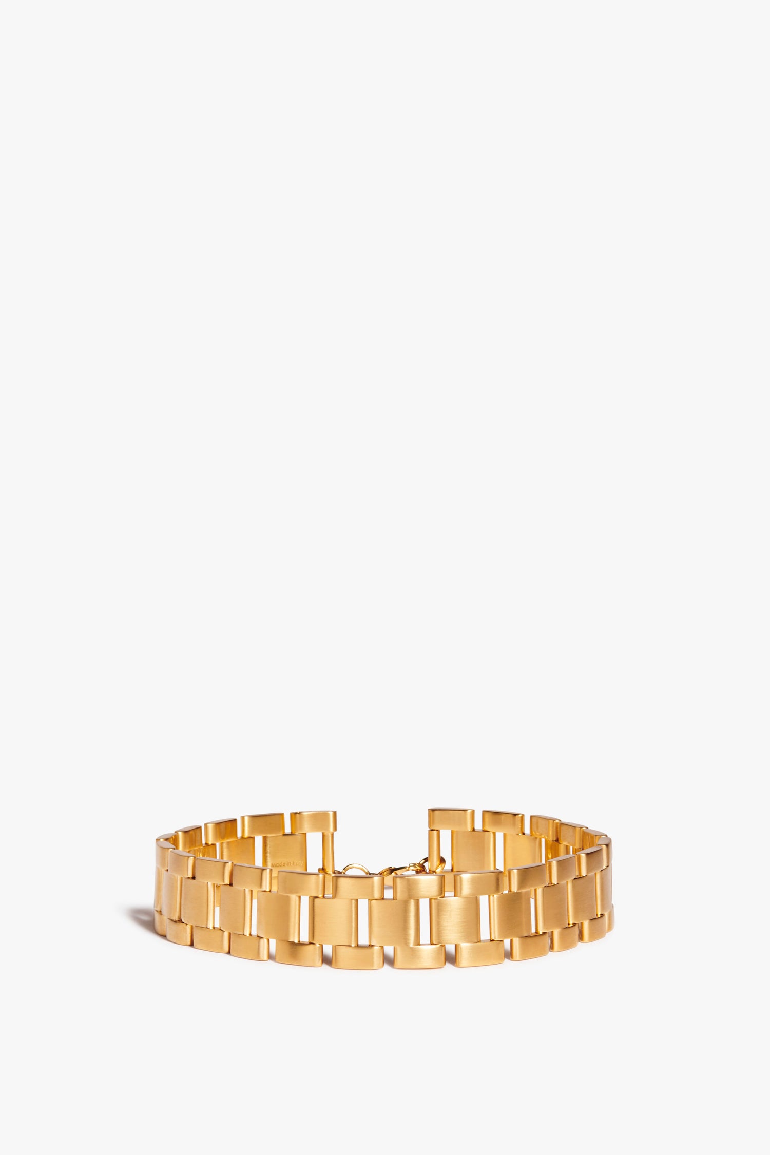 A wide gold bracelet with a linked design, reminiscent of a Watch Chain Choker In Gold by Victoria Beckham, displayed against a plain white background.