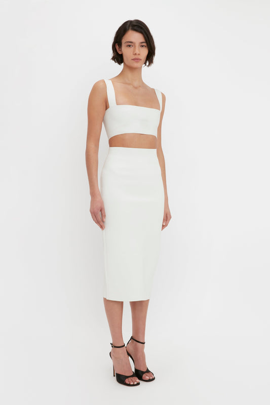 A woman in a stylish VB Body Strap Bandeau top and VB Body Fitted Midi Skirt with black heels poses against a plain white background.