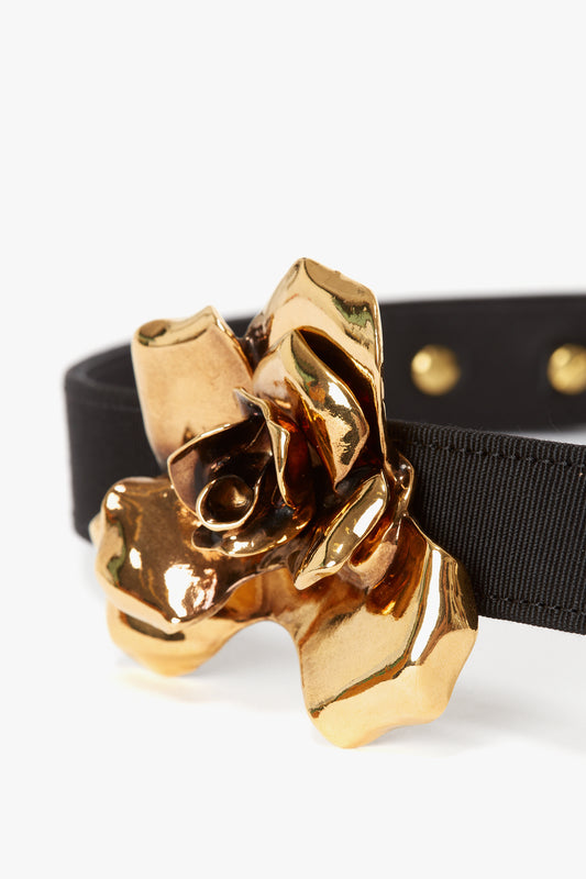 Exclusive Flower Belt In Black And Gold buckle on a black fabric belt against a white background.