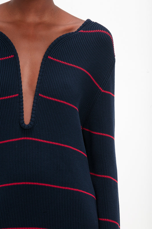 Close-up of a person wearing the Victoria Beckham Frame Detail Jumper Dress In Navy-Red, reminiscent of SS24 runway chic. The background is plain white.
