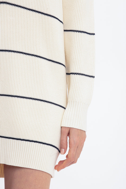 A person wearing a Victoria Beckham Frame Detail Jumper Dress In Natural-Navy. The image focuses on the sleeve and the side of the mid-weight knit garment.
