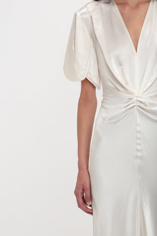 A woman wearing a Victoria Beckham Gathered V-Neck Midi Dress in Ivory, standing against a plain white background.