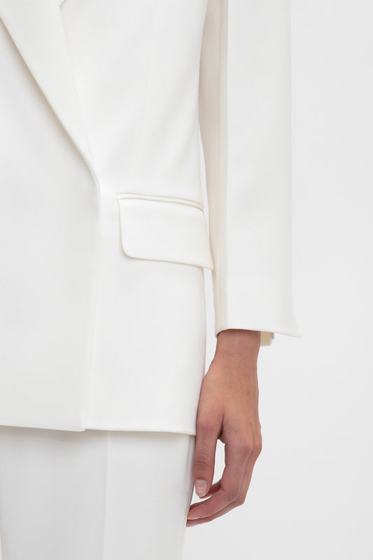 Close-up of a person wearing a white, Exclusive Double Breasted Tuxedo Jacket In Ivory by Victoria Beckham and matching pants. The person’s hand is visible at their side, highlighting a pocket on the jacket. Ideal for black-tie occasions, this ensemble exudes timeless elegance.