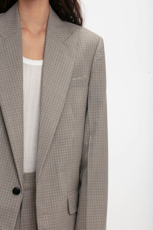 A person wearing a light brown Peak Lapel Jacket In Multi by Victoria Beckham with an oversized silhouette over a white shirt is shown from the shoulders down against a plain white background.