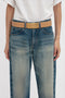 Person wearing a contemporary Victoria Beckham Jumbo Frame Belt In Camel Leather with a decorative buckle and gold hardware over blue jeans and a white shirt.