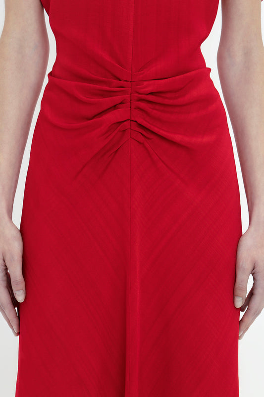 Close-up of a woman in a Victoria Beckham Exclusive Gathered V-Neck Midi Dress In Carmine, focusing on the detailed ruching at the back.