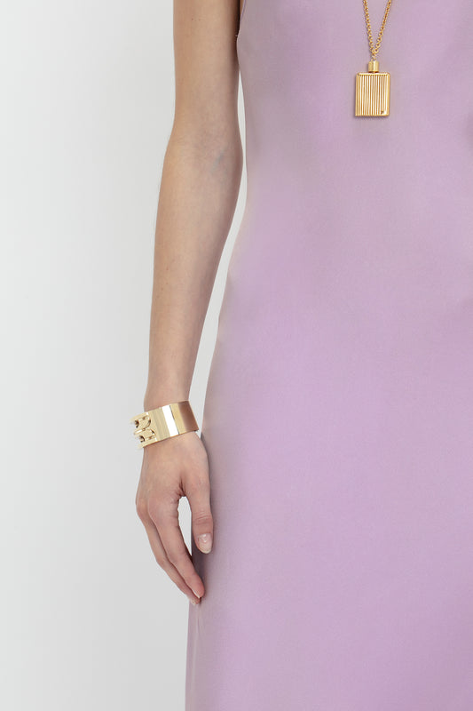 Woman wearing a Victoria Beckham Low Back Cami Floor-Length Dress In Rosa with a deep V neckline, complemented by a gold necklace and bracelet, focusing on jewelry and elegant attire.