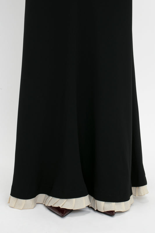 A V-Neck Gathered Waist Floor-Length Gown In Black by Victoria Beckham barely reveals a pair of burgundy shoes at the bottom, creating a flattering silhouette.