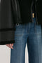 A person wearing blue jeans and a Shearling Jacket In Black by Victoria Beckham with fur trim on the cuffs and edges is shown from mid-thigh to chest.