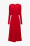 A long-sleeved, knee-length red dress with a fitted waist and a round neckline, featuring an elegant silhouette and a zipper closure at the back. The Dolman Midi Dress In Red by Victoria Beckham.