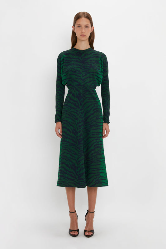 Woman in a Victoria Beckham Dolman Midi Dress In Green-Navy Tiger Print with long sleeves and a round neck, standing against a white background.