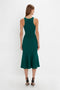 A woman with long brown hair is wearing a sleeveless, green VB Body Sleeveless Dress In Lurex Green by Victoria Beckham featuring a flared silhouette and black high-heeled shoes, shown from the back against a white background. Perfect for updating your new-season wardrobe.
