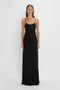 A person stands against a white background, wearing a Floor-Length Cami Dress In Black by Victoria Beckham.