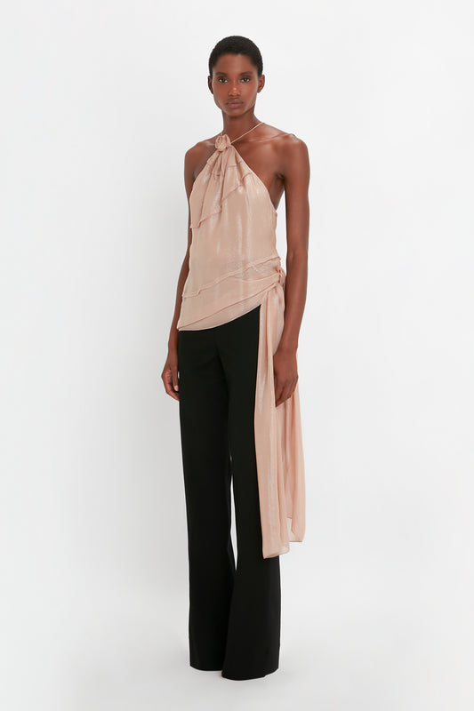 Person wearing a beige, Flower Detail Cami Top In Rosewater from Victoria Beckham paired with black satin panel straight leg trousers, standing against a white background.