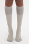 A person wearing Victoria Beckham Superfine Rib Socks In Lunar Grey made from 100% cotton, standing on a white background.